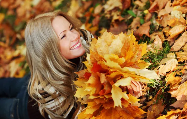 Картинка осень, трава, взгляд, листья, девушка, улыбка, джинсы, блондинка, лежит, свитер